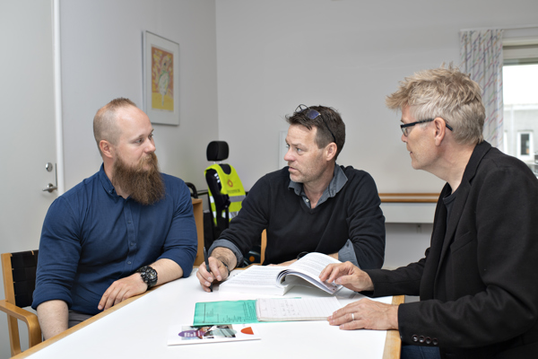 Tre ansatte i HandicapBilistCentret sidder om et bord og sagsbehandler. I HandicapBilistCentret er der fokus på tværfaglighed og trivsel blandt de ansatte..