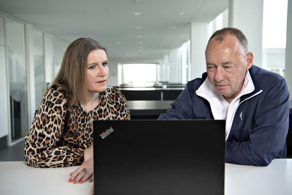 Mand og kvinde sidder og taler sammen foran en computer.